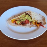 Chicken Fajitas in a Whole Wheat Pita Pocket filled with juicy chicken, bell peppers, and creamy avocado, served on a white plate.