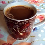 A cozy cup of homemade Cinnamon Dolce Latte served in a decorative mug on a floral tablecloth, showcasing its rich, creamy texture. Perfect for enjoying a warm and comforting coffeehouse-style drink at home.