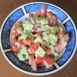 a bowl of salad with tomatoes, avocado and onion