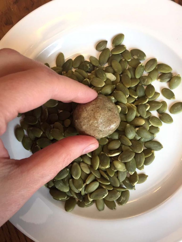 rolling energy balls in pumpkin seeds