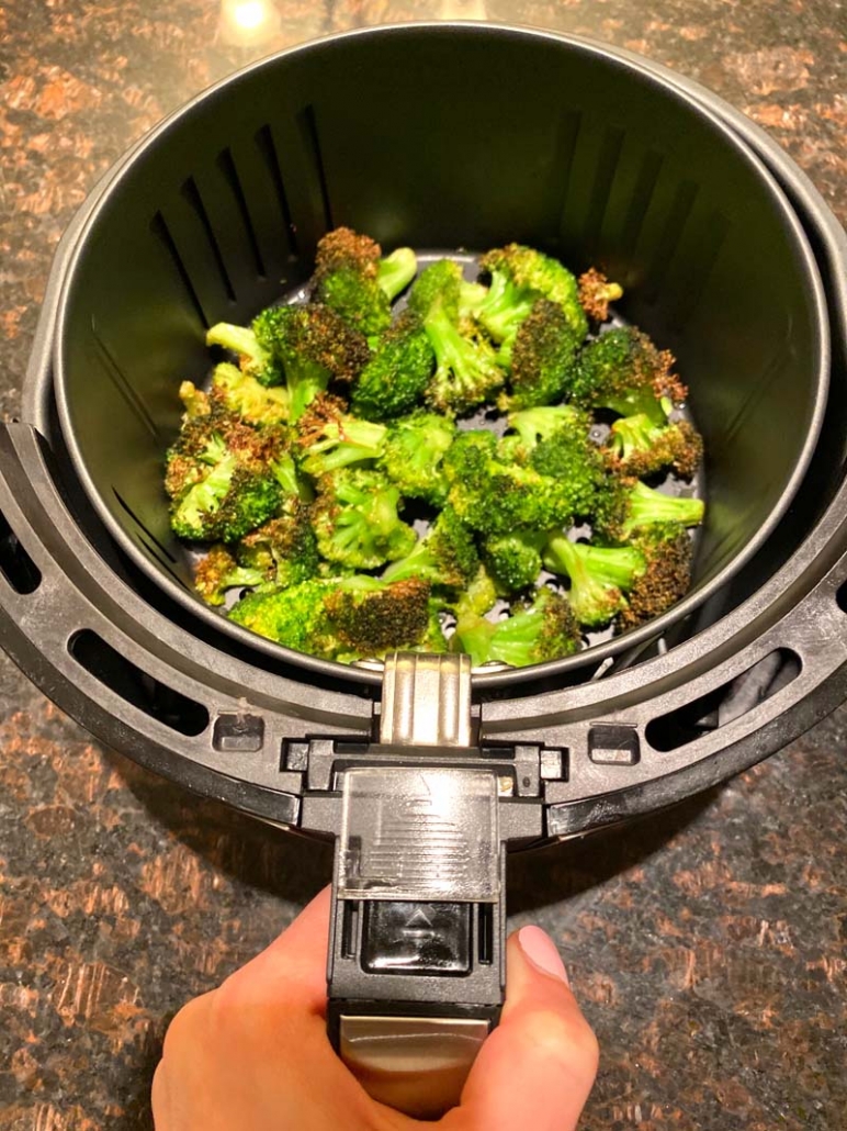 Fried broccoli in an air fryer basket