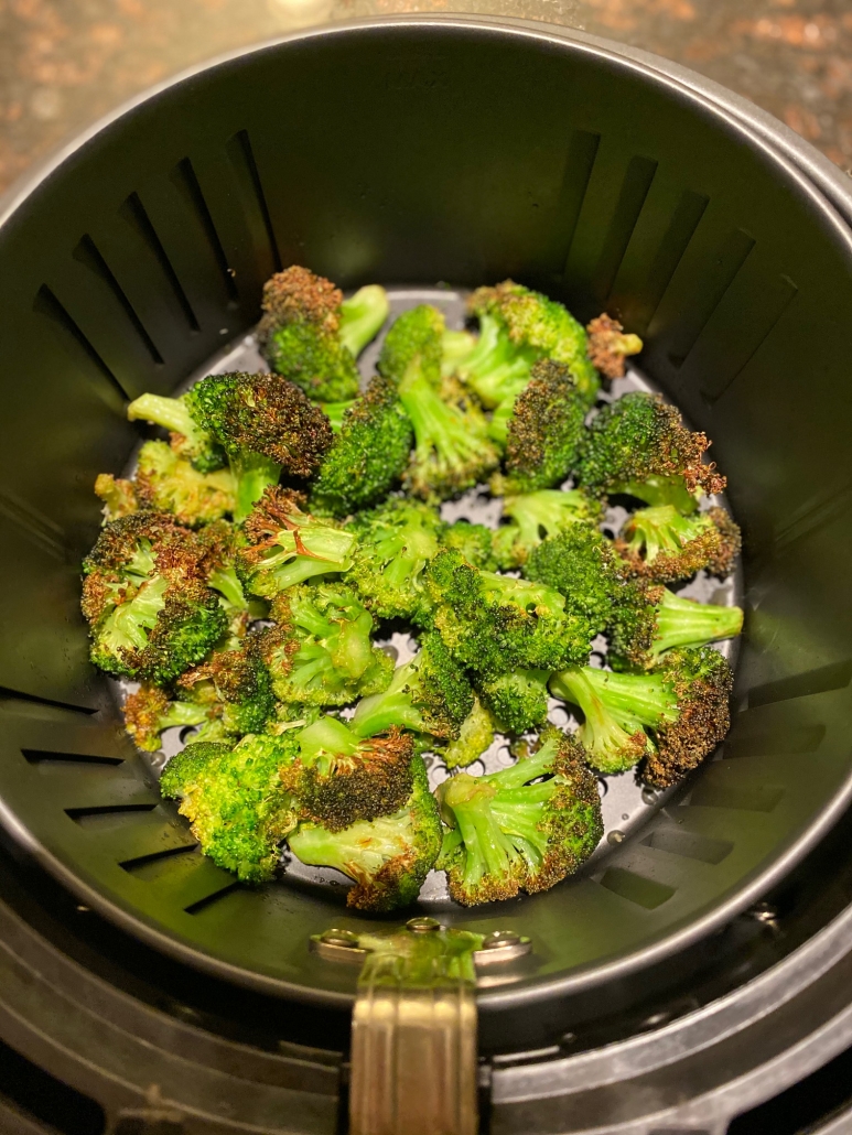 fried roasted broccoli in an air fryer basket