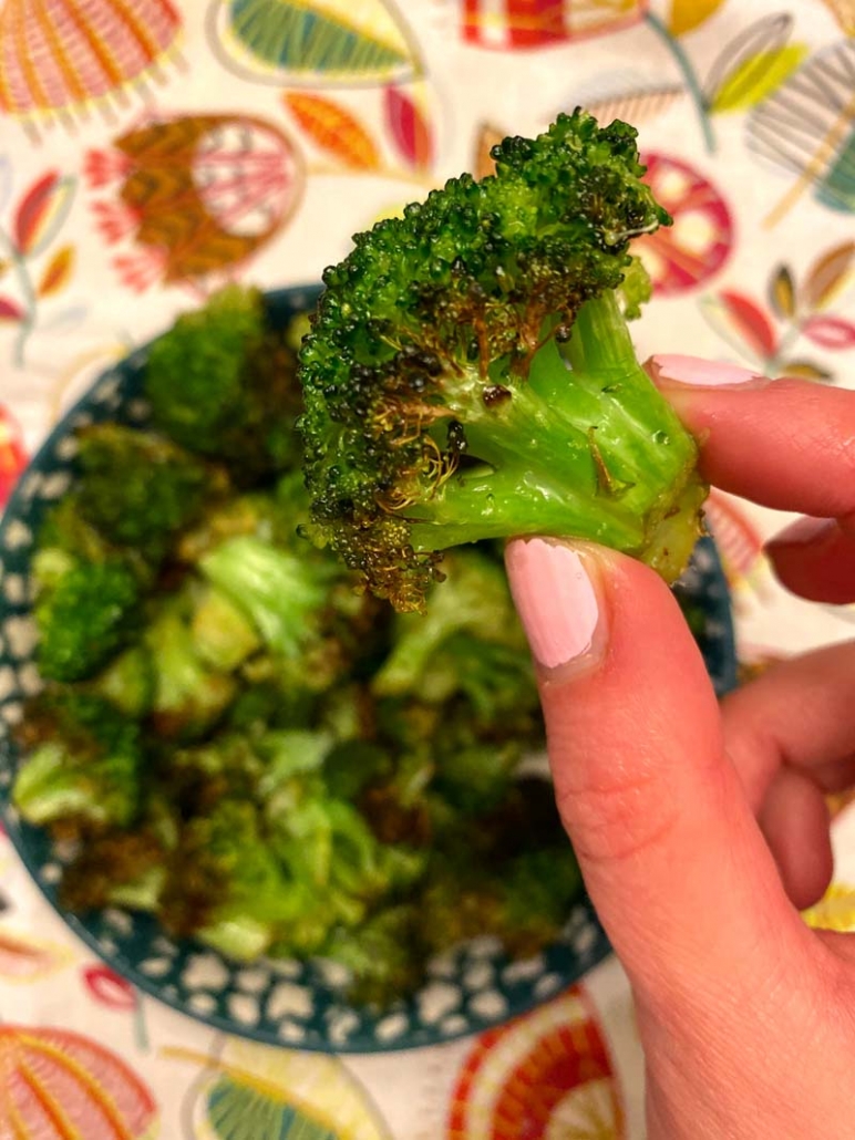 holding a roasted broccoli floret