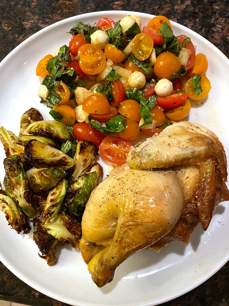 cornish hen with roasted brussel sprouts and heirloom caprese salad