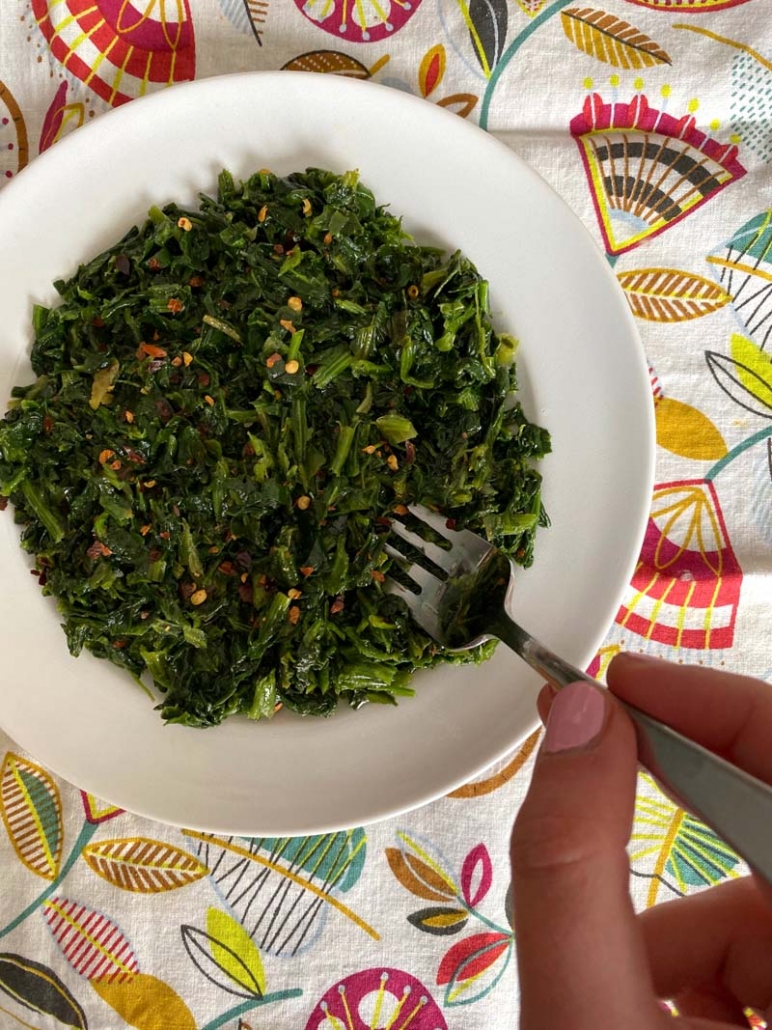 eating spicy sauteed spinach with a fork