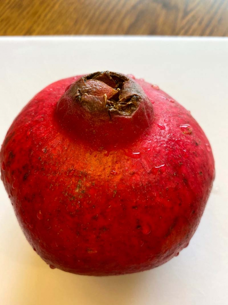 Ripe pomegranate on a white cutting board ready to cut