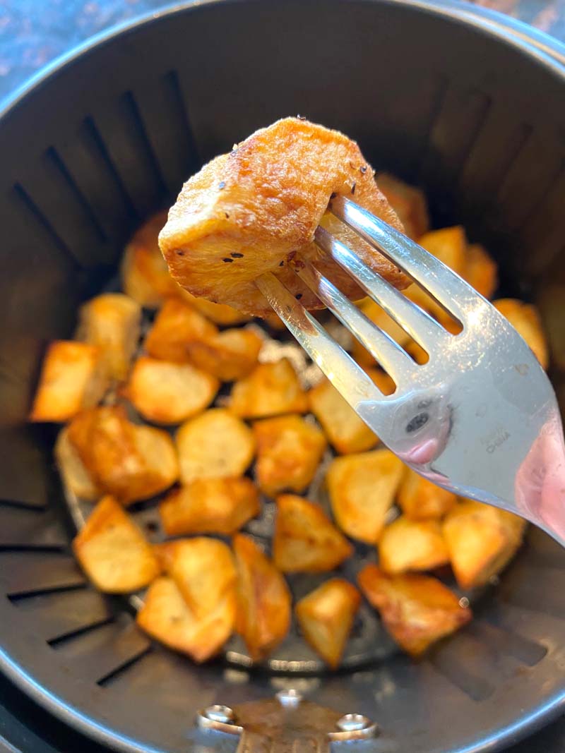 A roasted potato on a fork over the air fryer