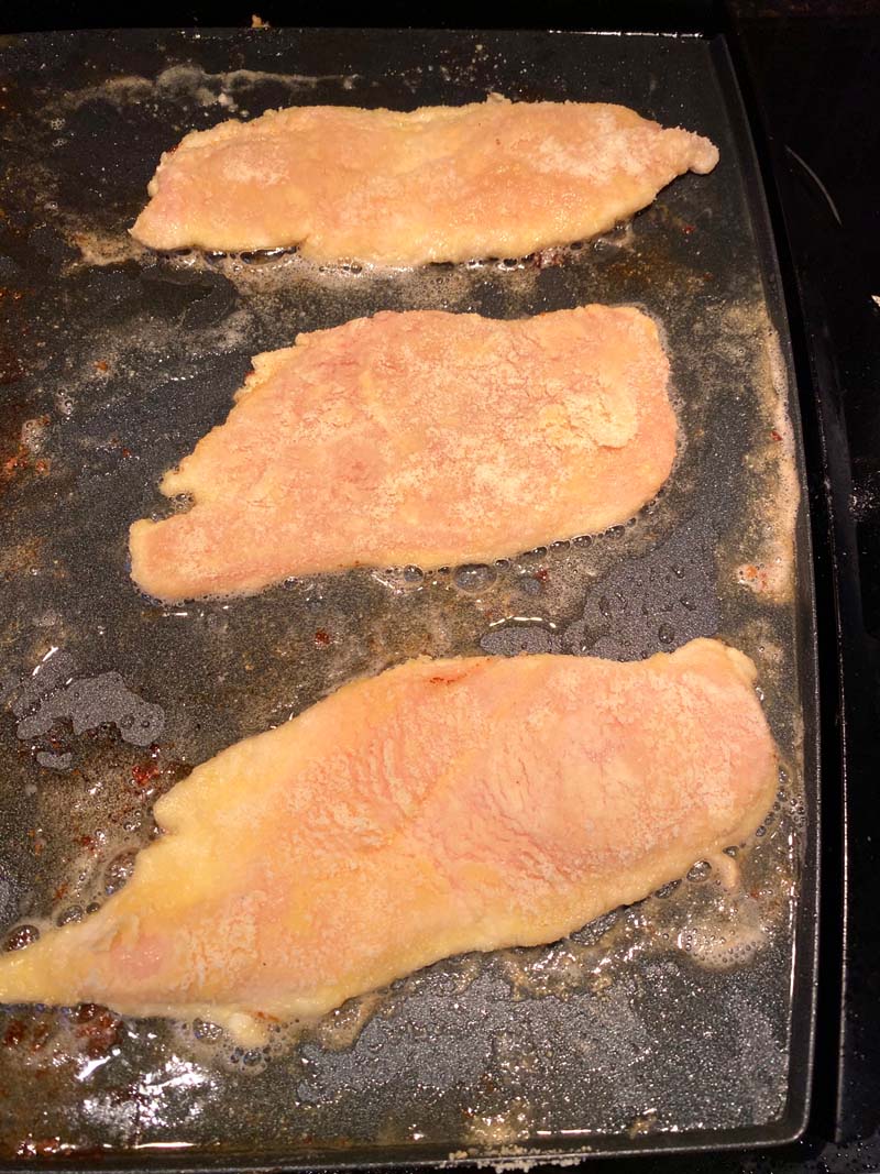 Three pieces of chicken on a griddle