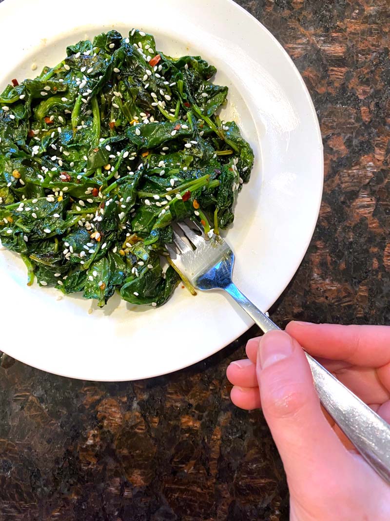 Eating the sautéed kale with a fork