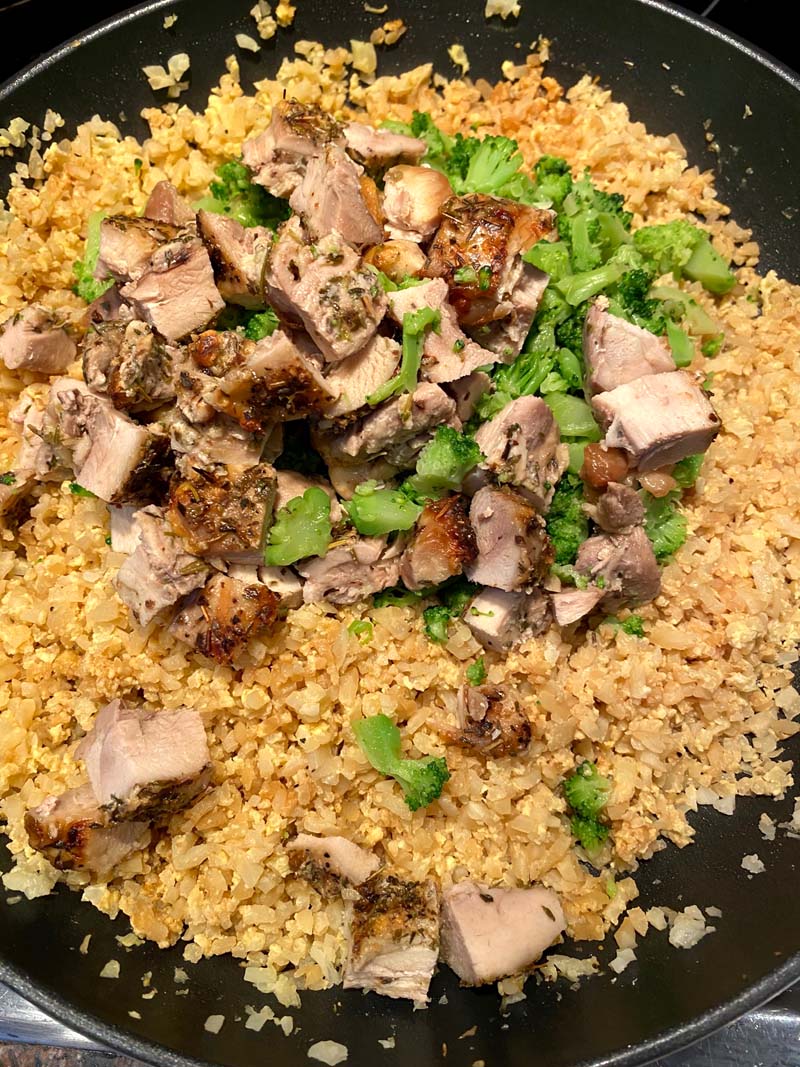 ingredients for chicken cauliflower fried rice being cooked together in a wok