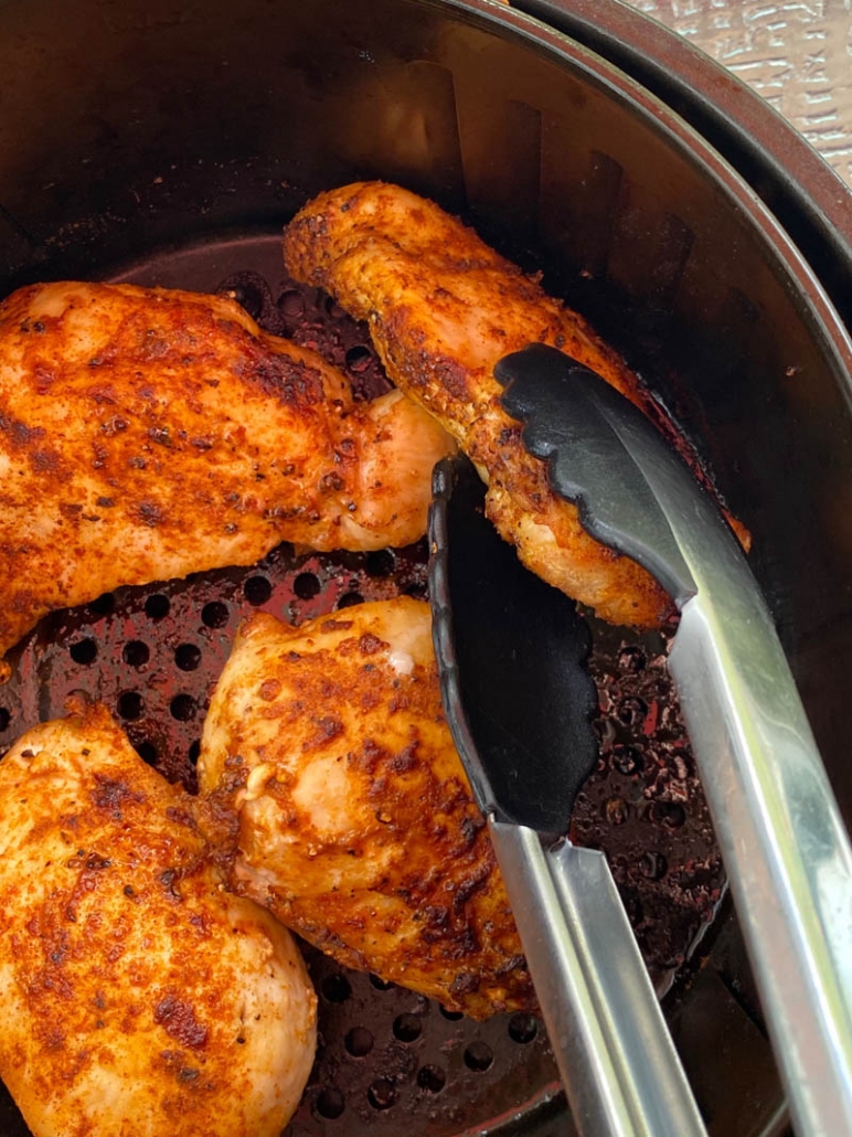 using tongs to flip chicken breasts in the air fryer basket