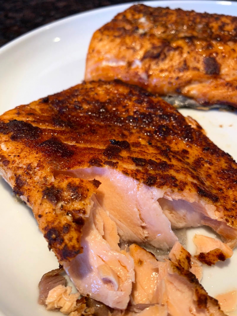 two pieces of salmon on a white plate. 