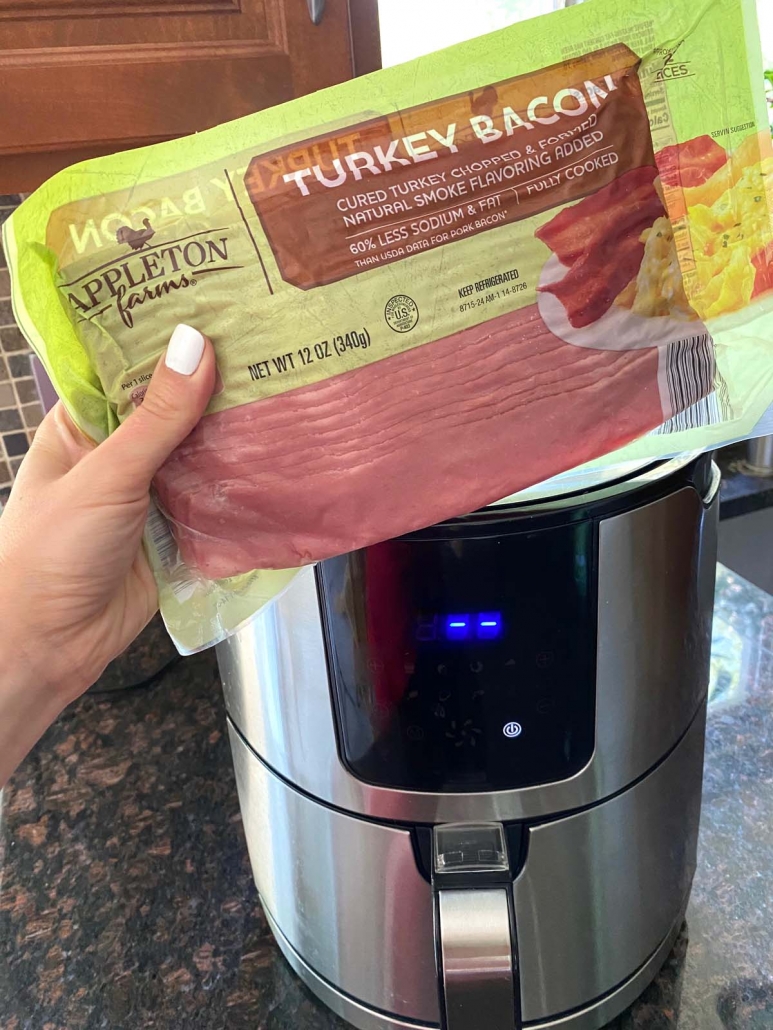 hand holding package of turkey bacon in front of air fryer