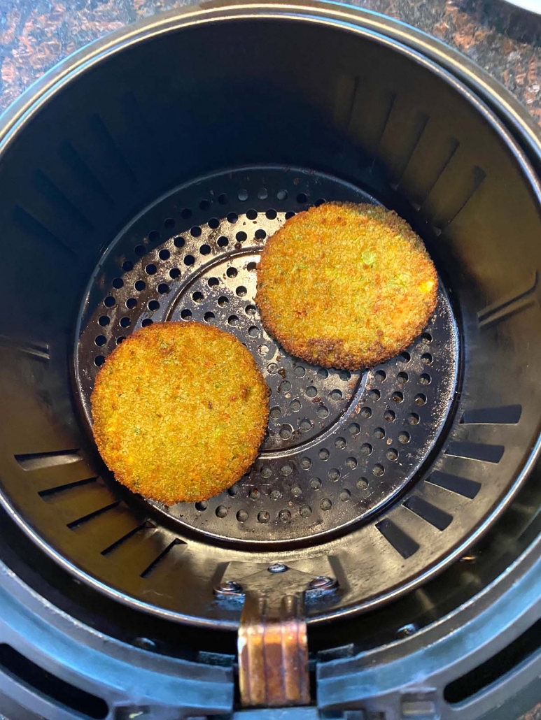 two frozen veggie burgers in an air fryer