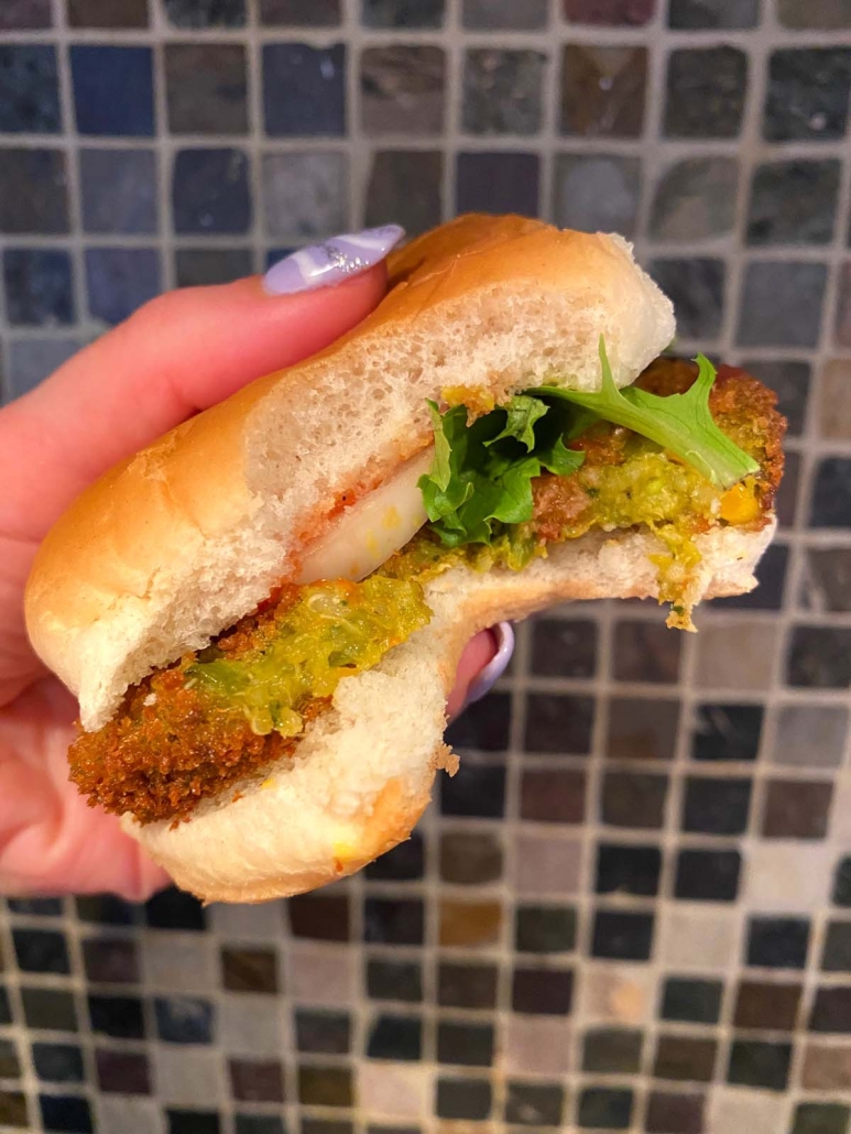 hand holding veggie burger in bun with lettuce and onion