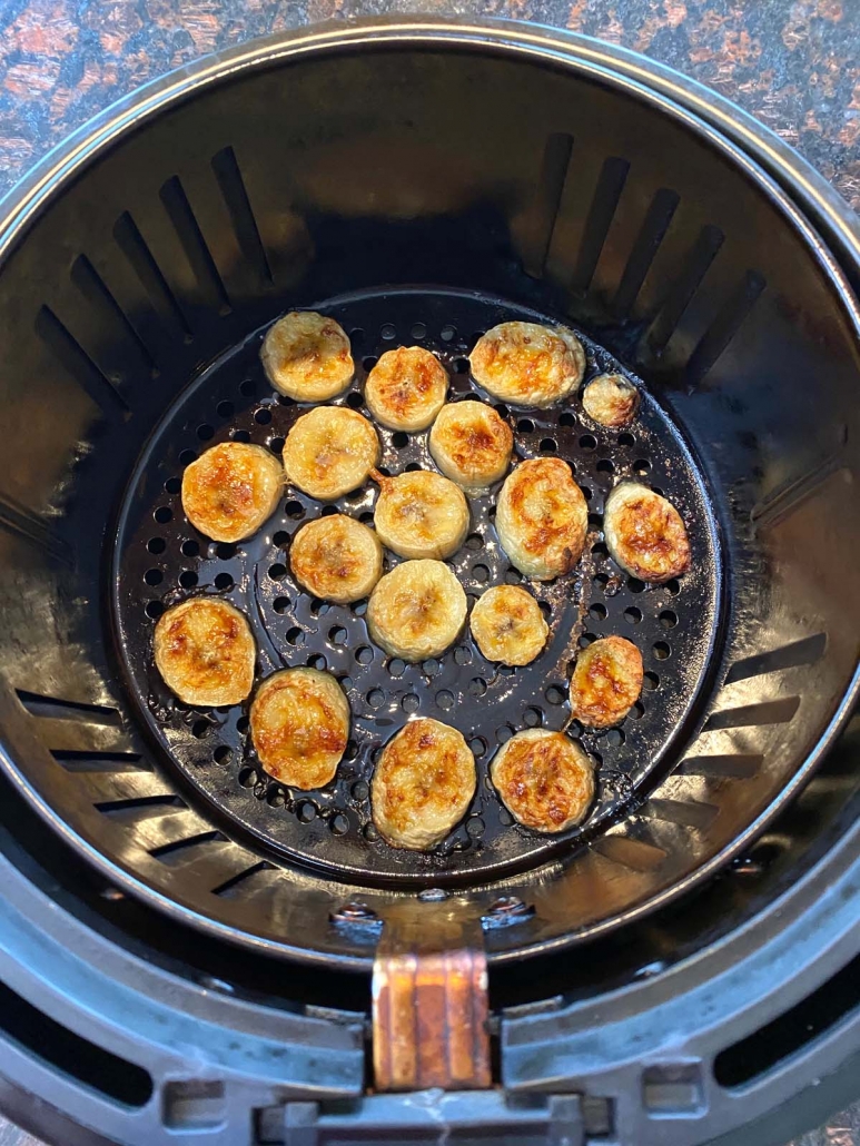 air fryer basket with sliced banana cooking inside