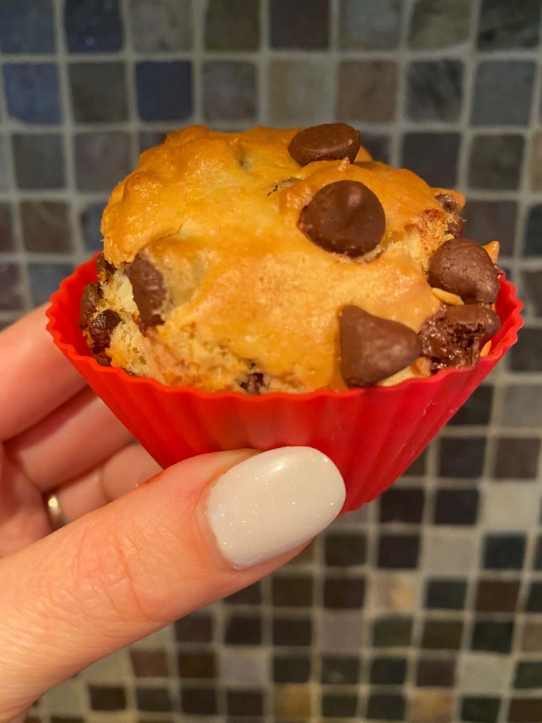 hand holding a chocolate chip muffin in front of tiles