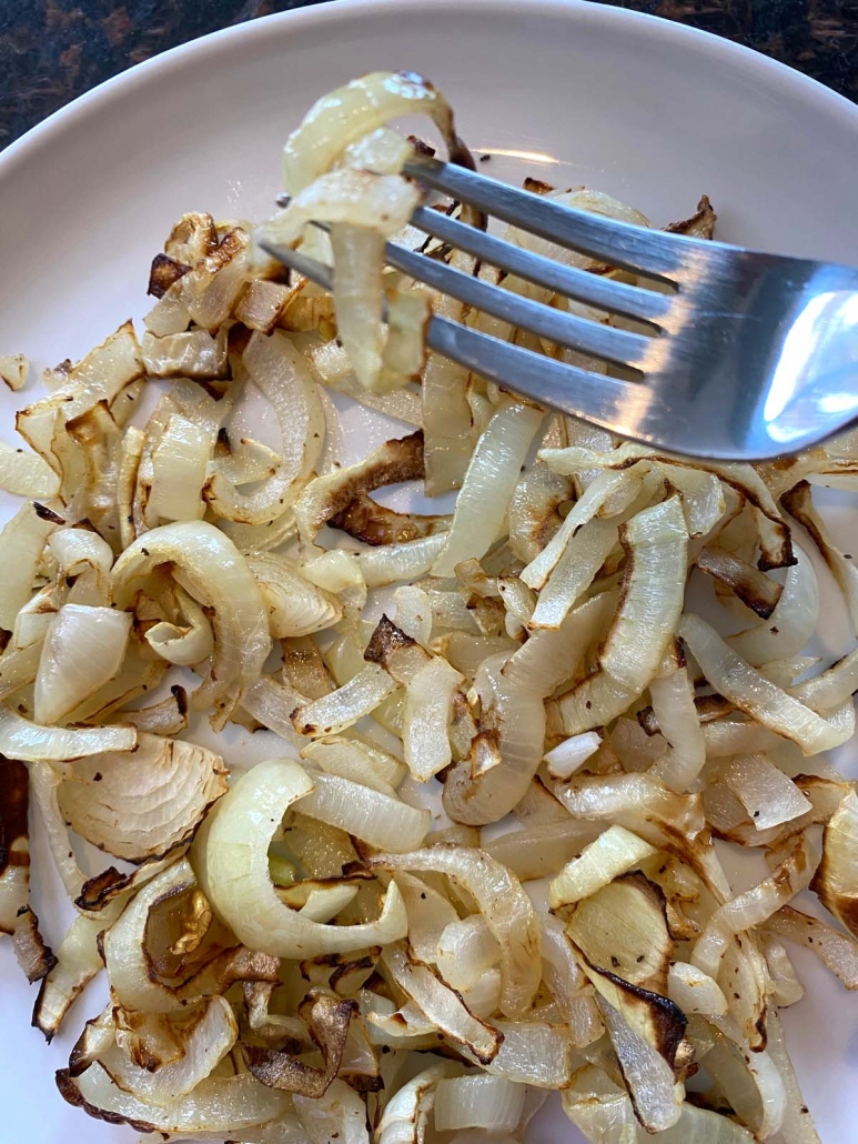 fork picking up some air fried onions from a plate