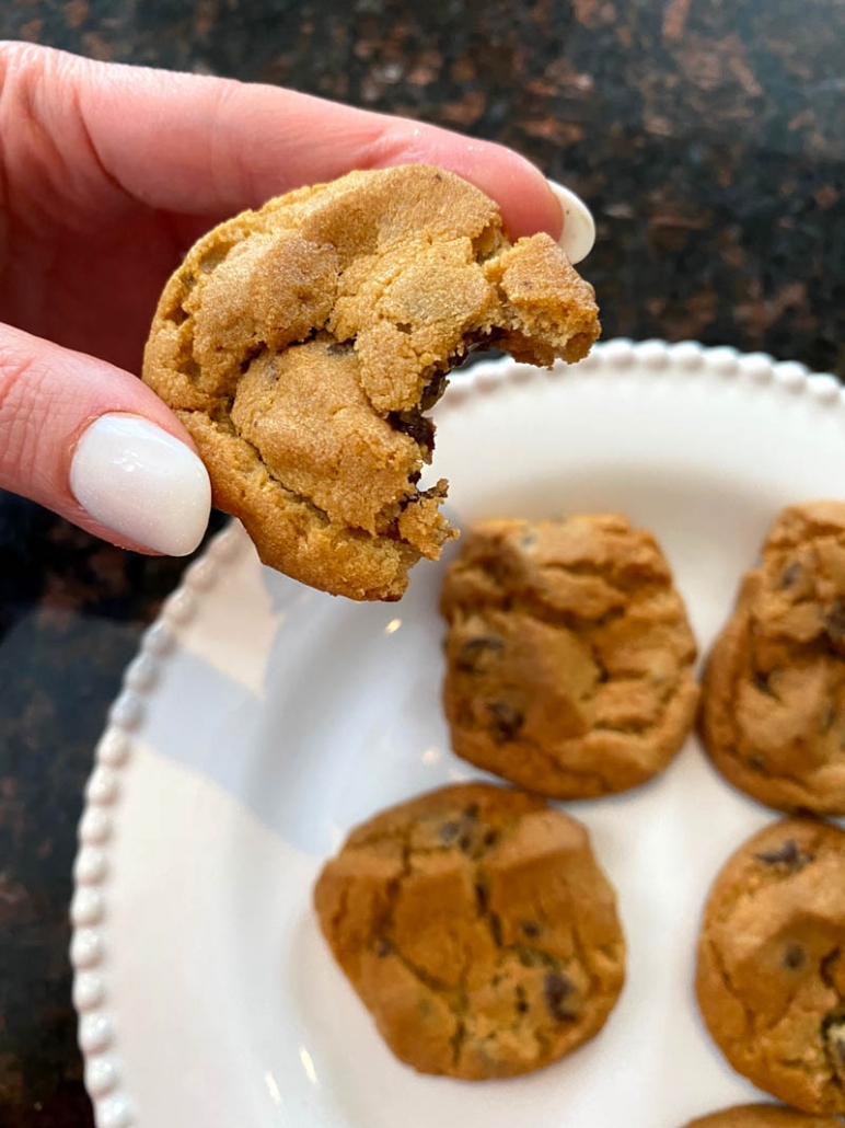 hand holding cookie with bite taken out above plate of cookies