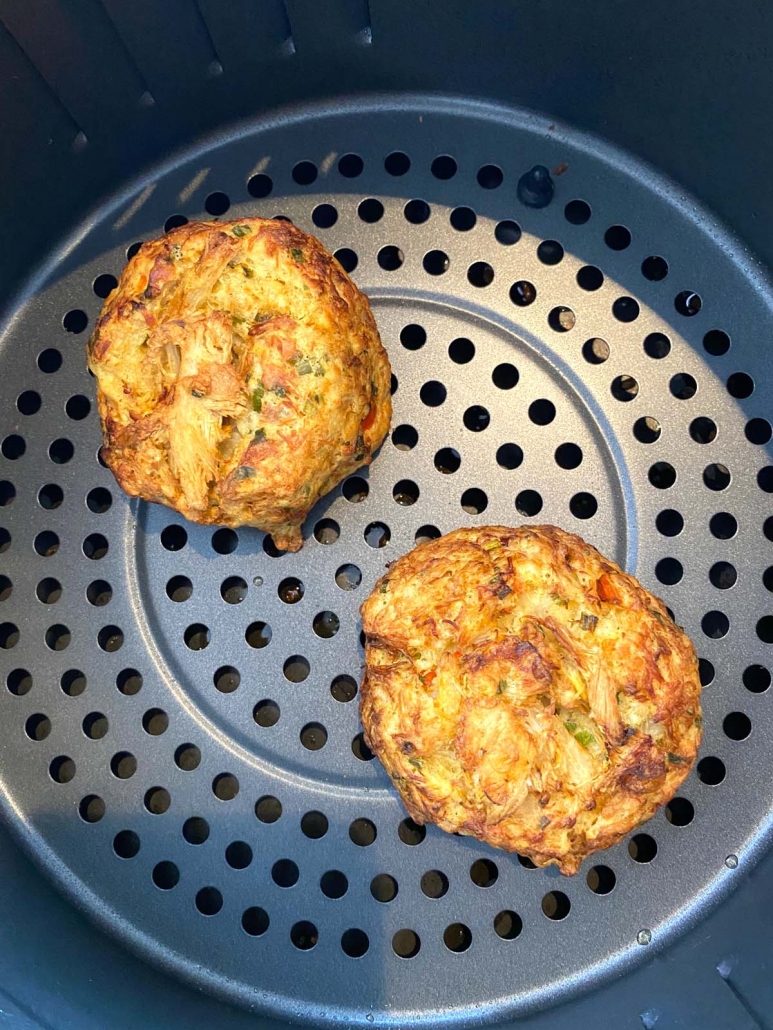 close up of two air fried crab cakes in the air fryer basket