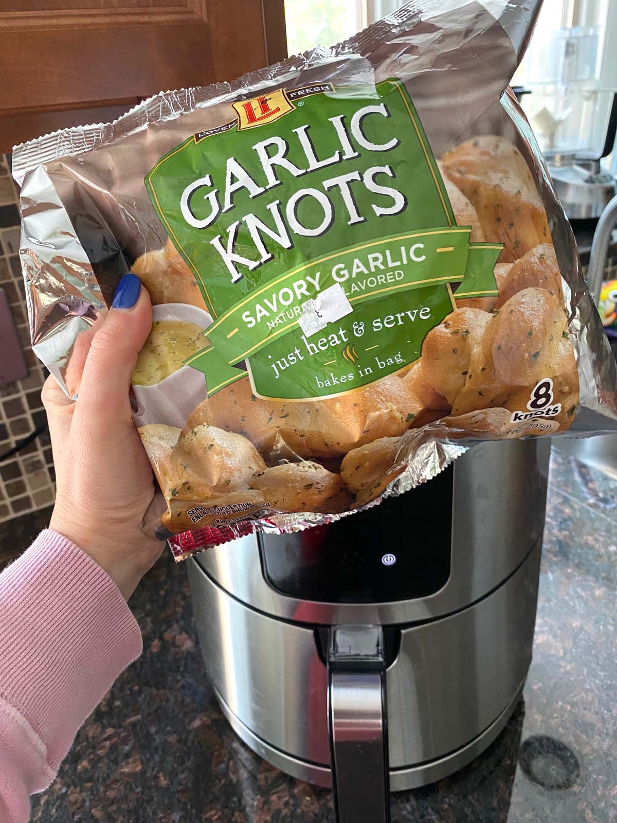 Bag of frozen garlic knots in front of an air fryer. 