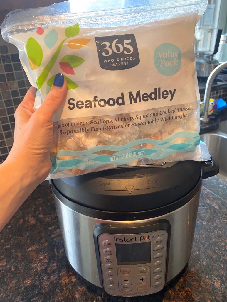 hand holding bag of frozen seafood medley above instant pot