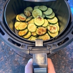 Air fryer roasted zucchini slices in the air fryer basket.