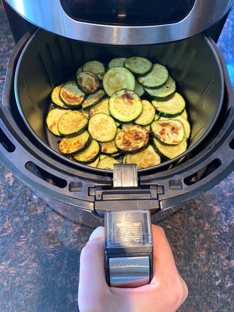 Air fryer roasted zucchini slices in the air fryer basket.