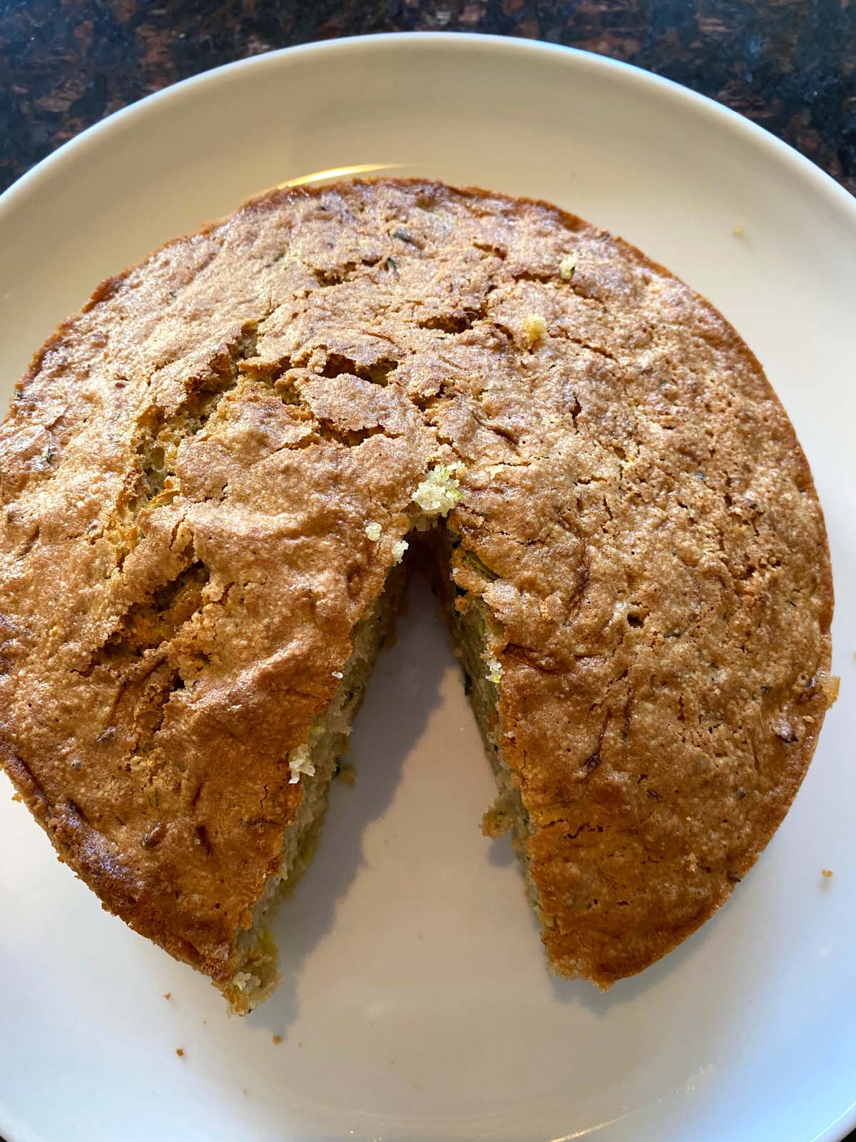 Air fryer zucchini bread on a white plate with a slice cut out.