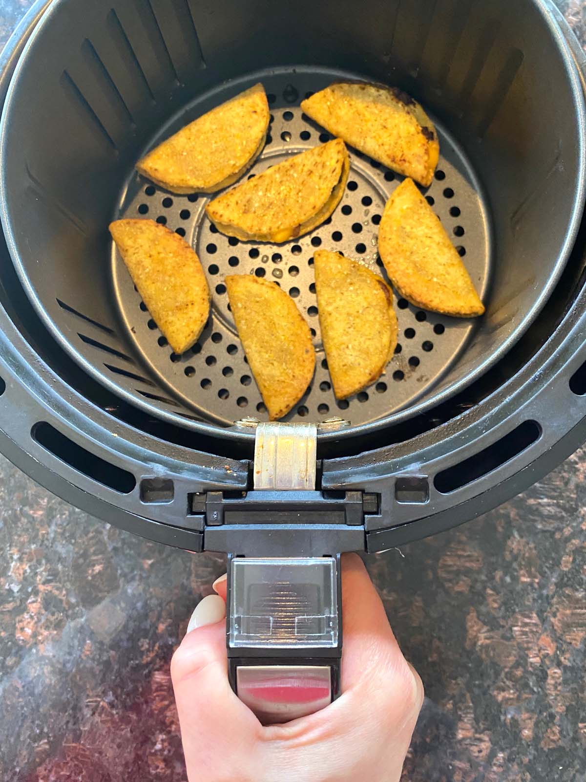 The basket of an air fryer completely removed with recipe inside.