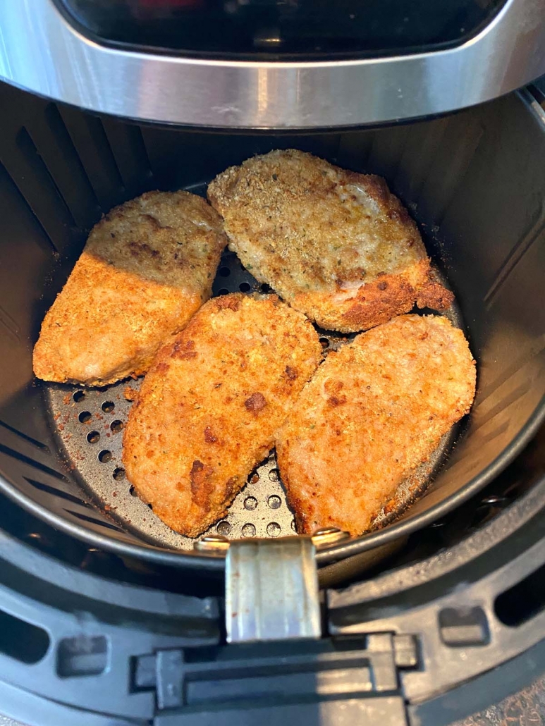 opened air fryer to show breaded pork chops