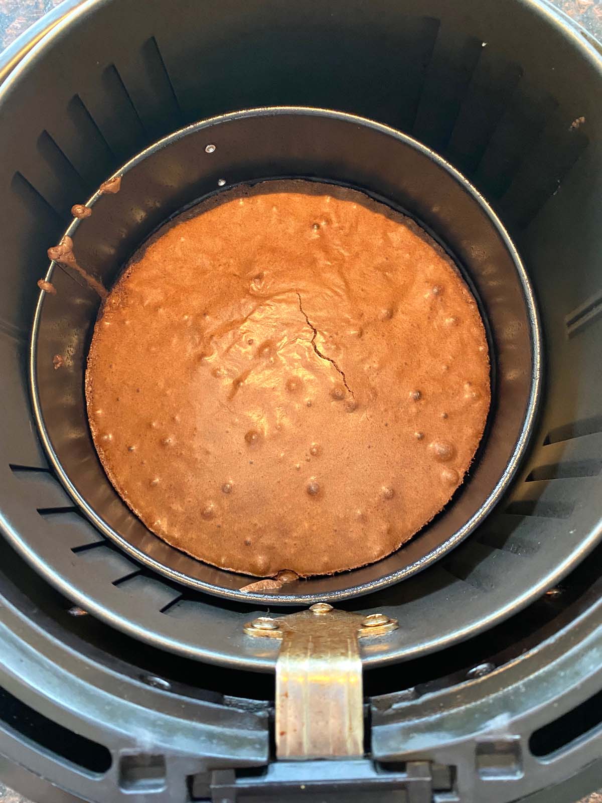 Overhead shot of cooked brownie in a springform pan placed in an air fryer basket.