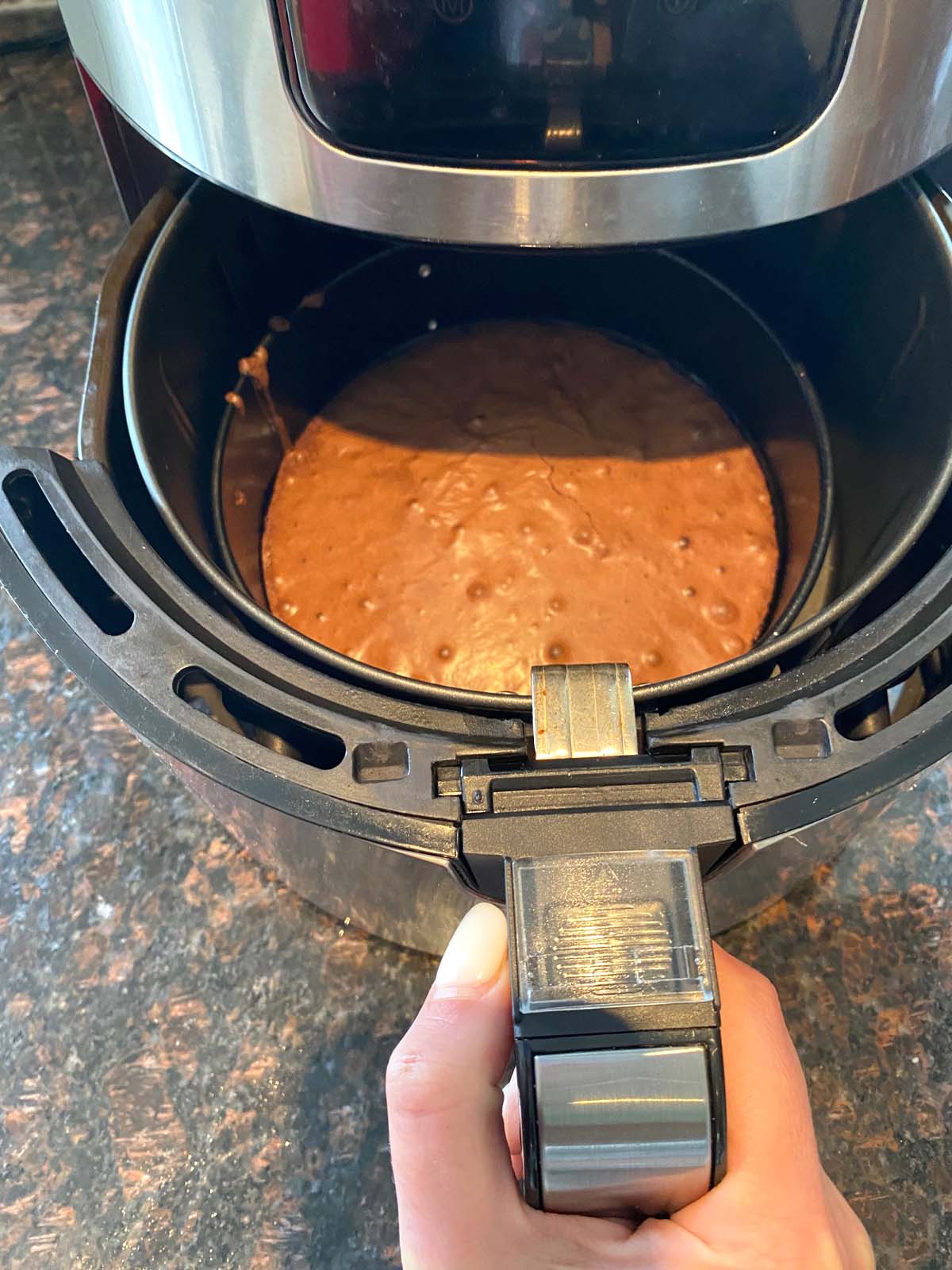 Pulling cooked brownie out of the air fryer.