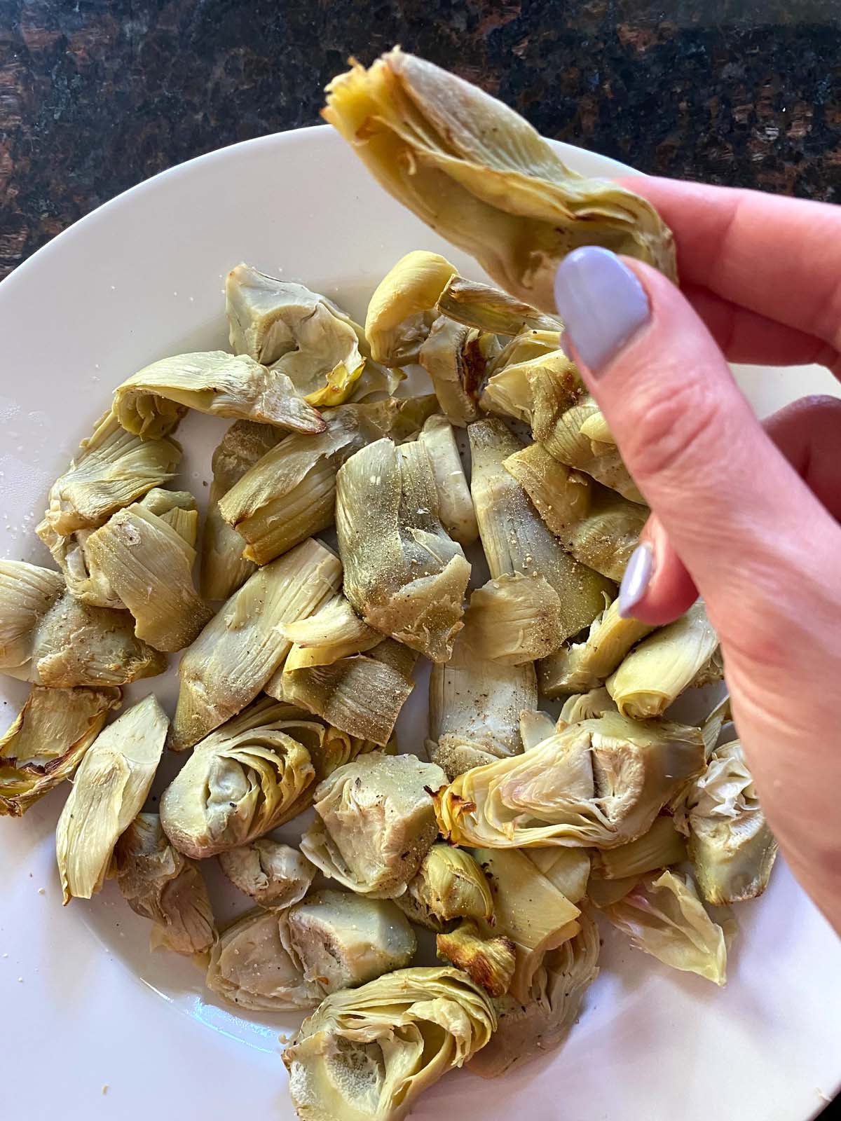 Cooked artichoke hearts on a white plate.