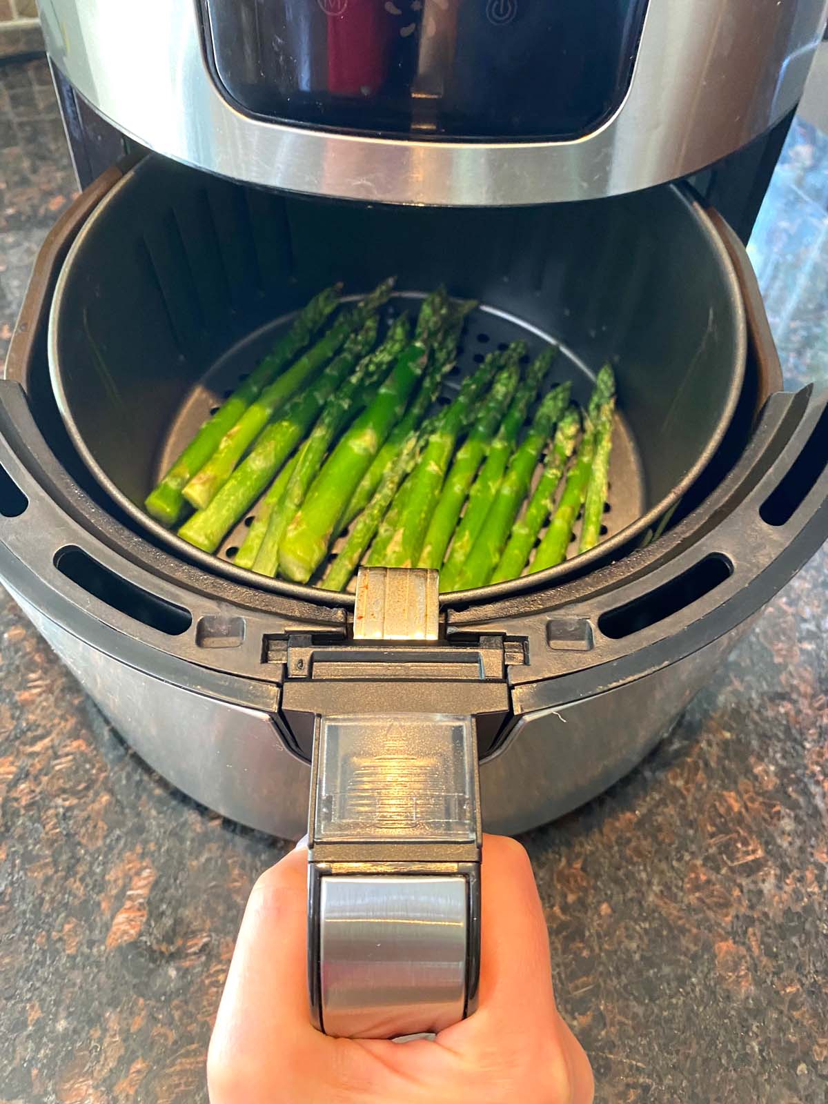 Cooked asparagus in an air fryer.