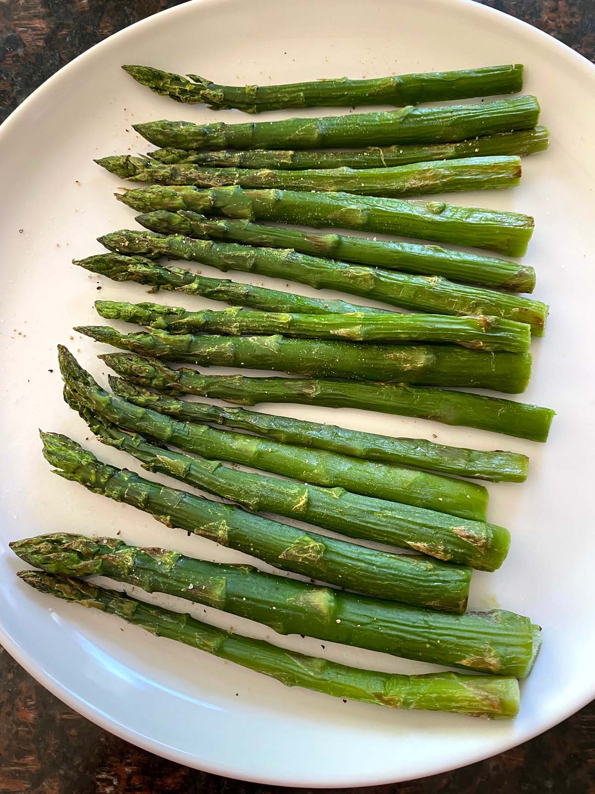 Cooked asparagus on a white plate.