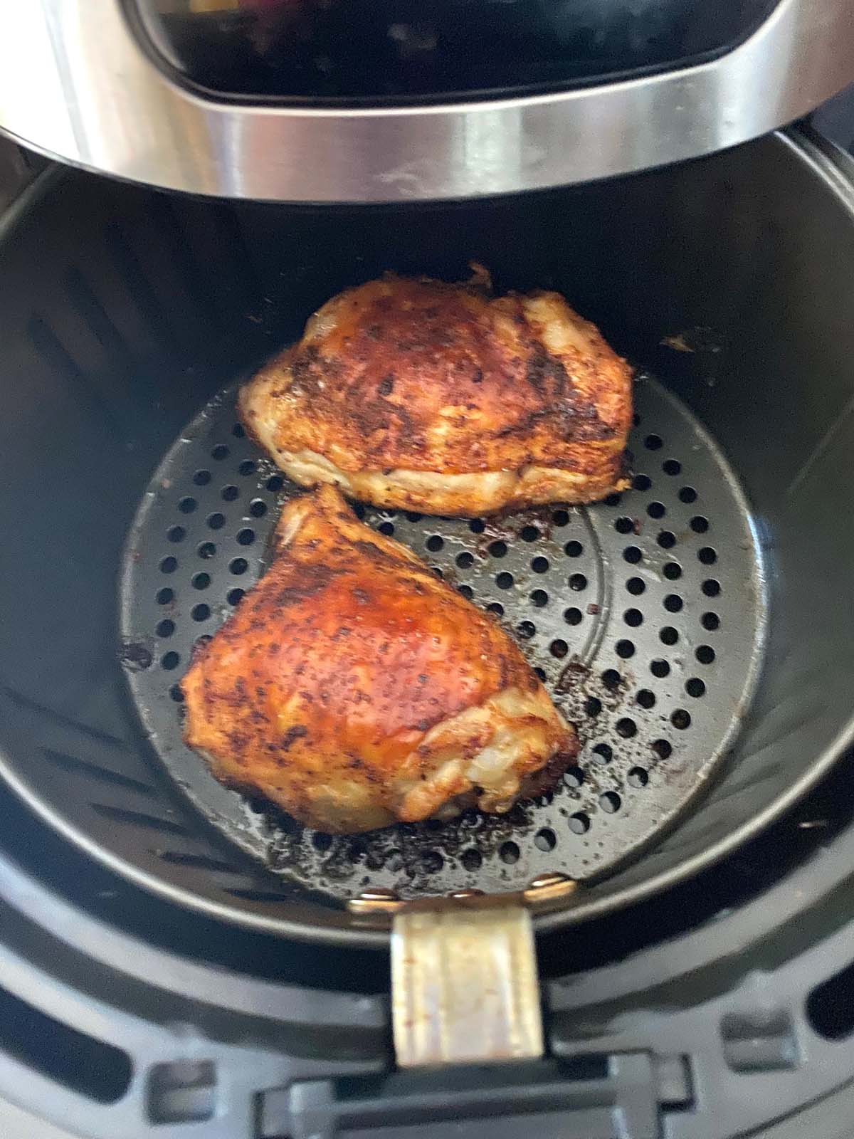 Cooked chicken thighs in an air fryer.