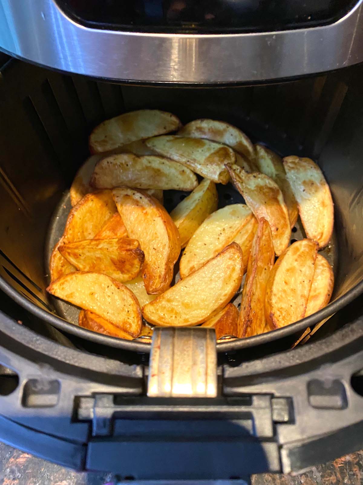 Cooked potato wedges in an air fryer.