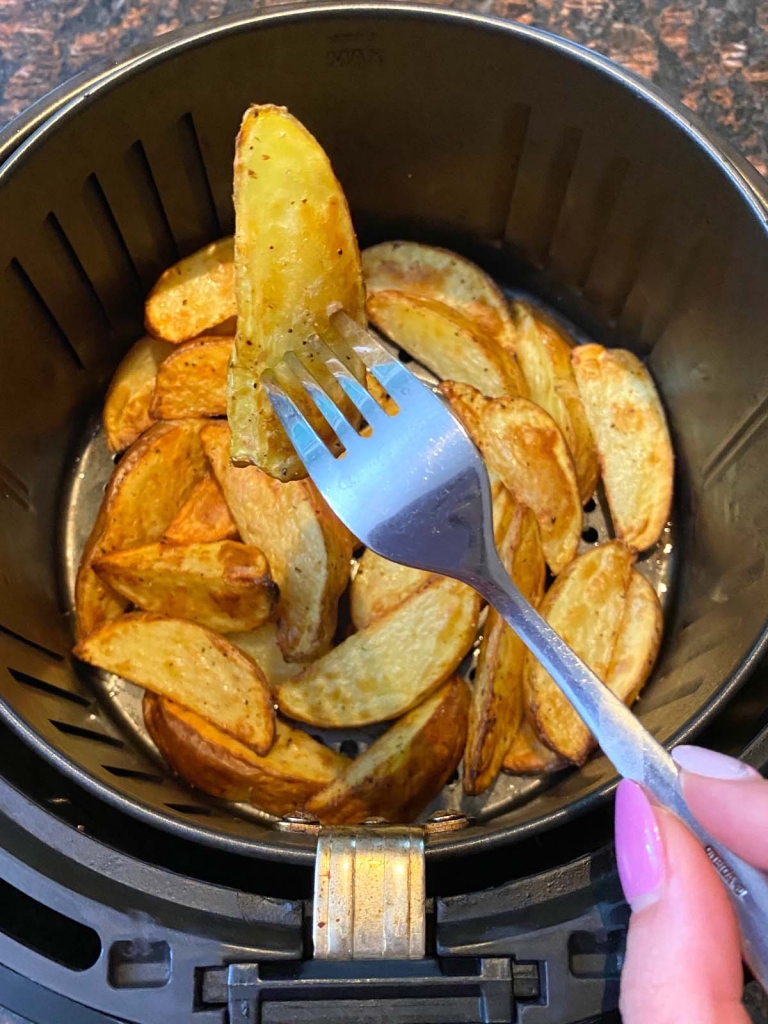 potato wedges in an air fryer with fork