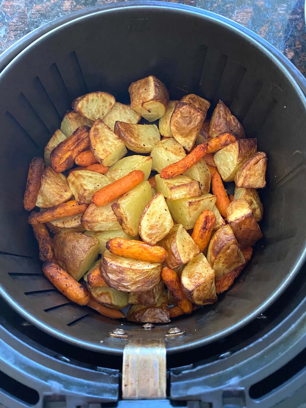 Roasted potatoes and carrots in an air fryer.