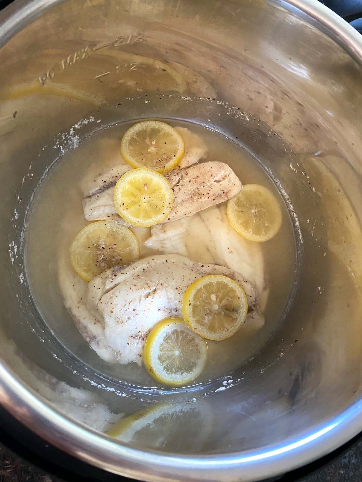 Fish in pot with water and lemon slices.