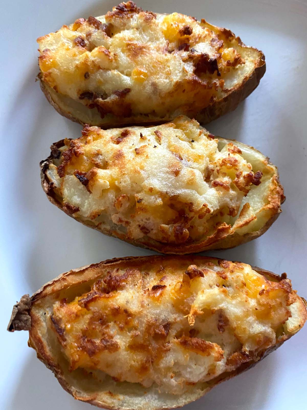 Twice baked potatoes on a white plate.