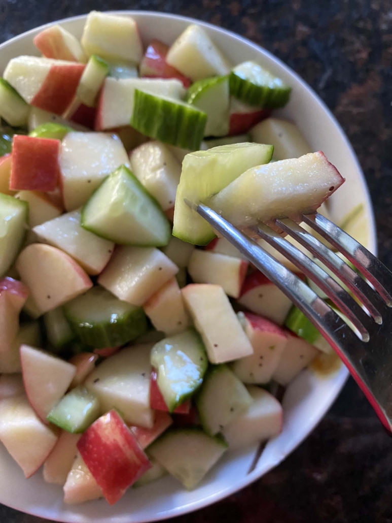 fork holding slices of apple and cucumber