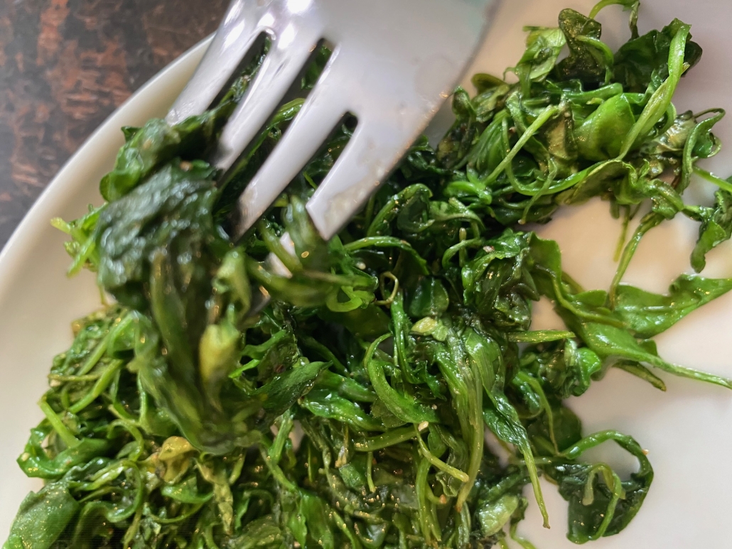 fork in sautéed arugula on plate