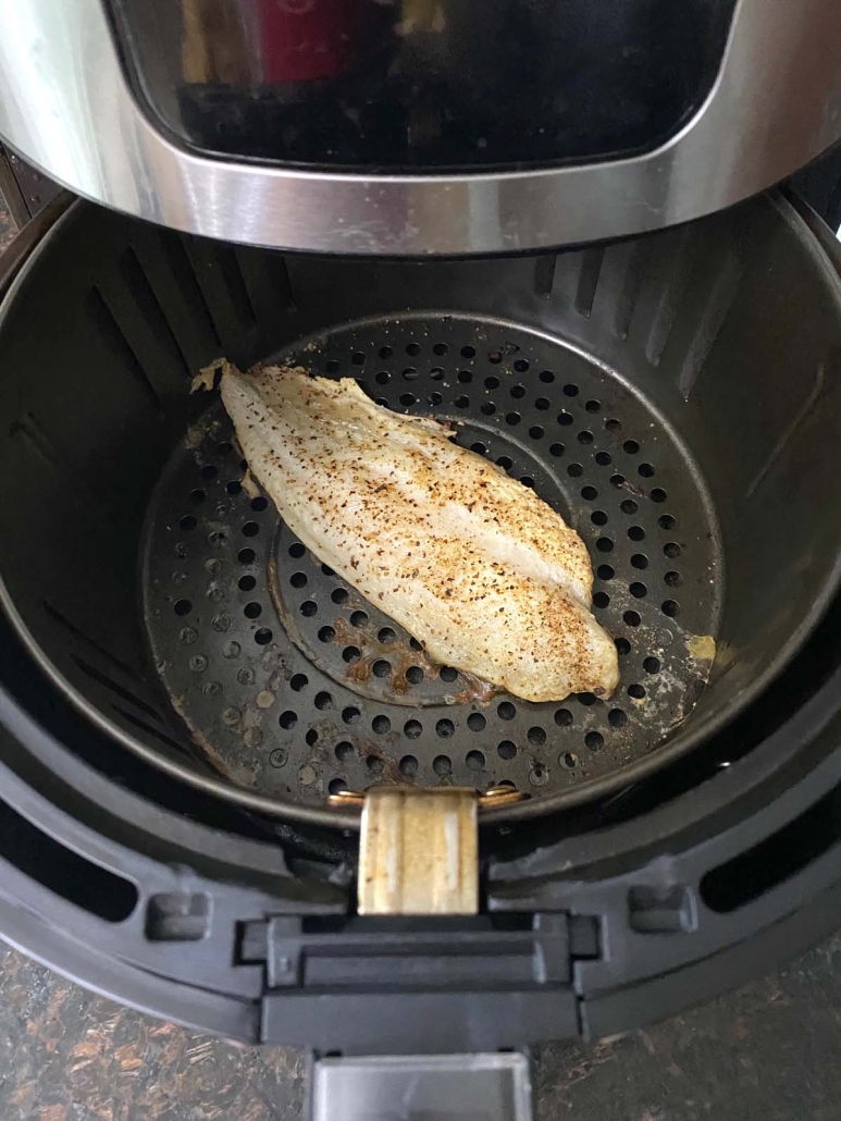 air fryer opened to show seasoned fish inside