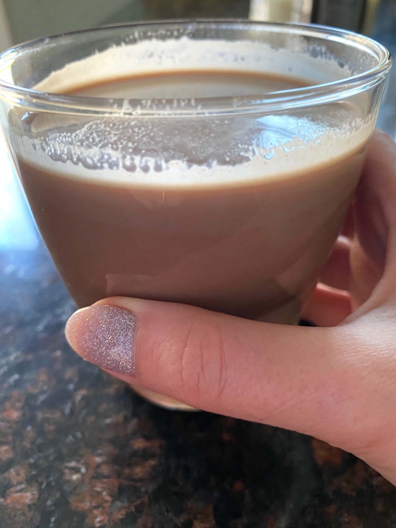 hand holding glass of chocolate milk