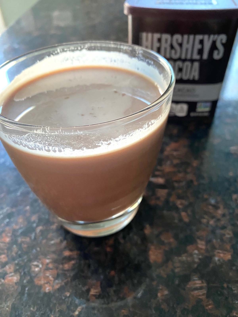 glass of chocolate milk in front of cocoa powder