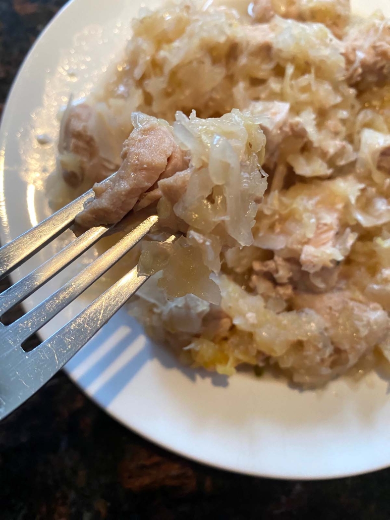 fork holding piece of cooked Instant Pot Pork And Sauerkraut