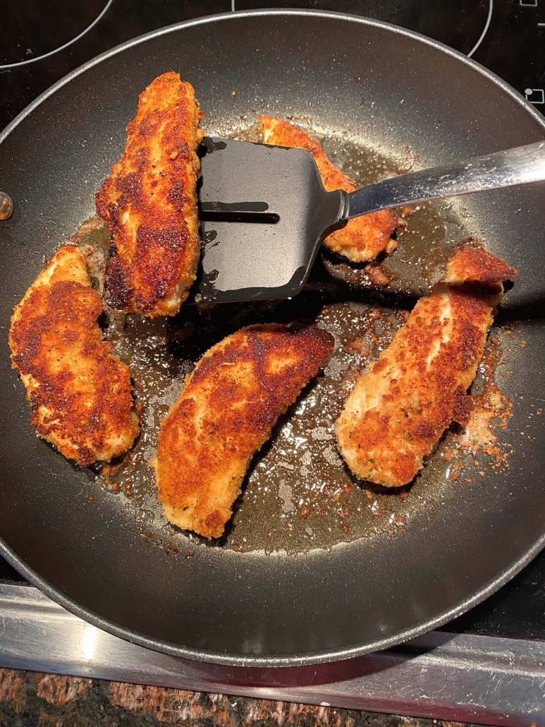 spatula holding piece of pan fried chicken tender