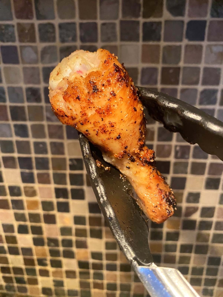 tong holding a pan fried drumstick